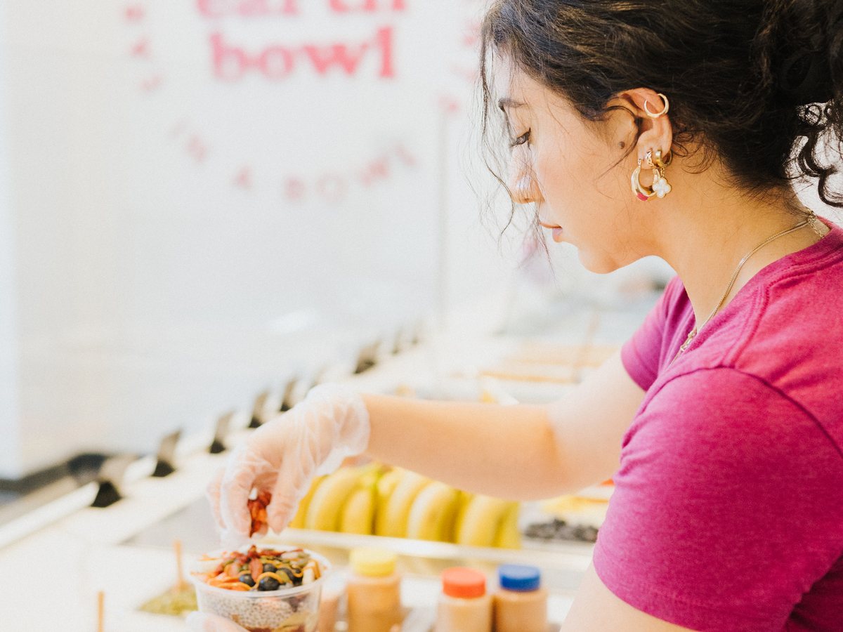 Team member adding superfood toppings to a chia bowl