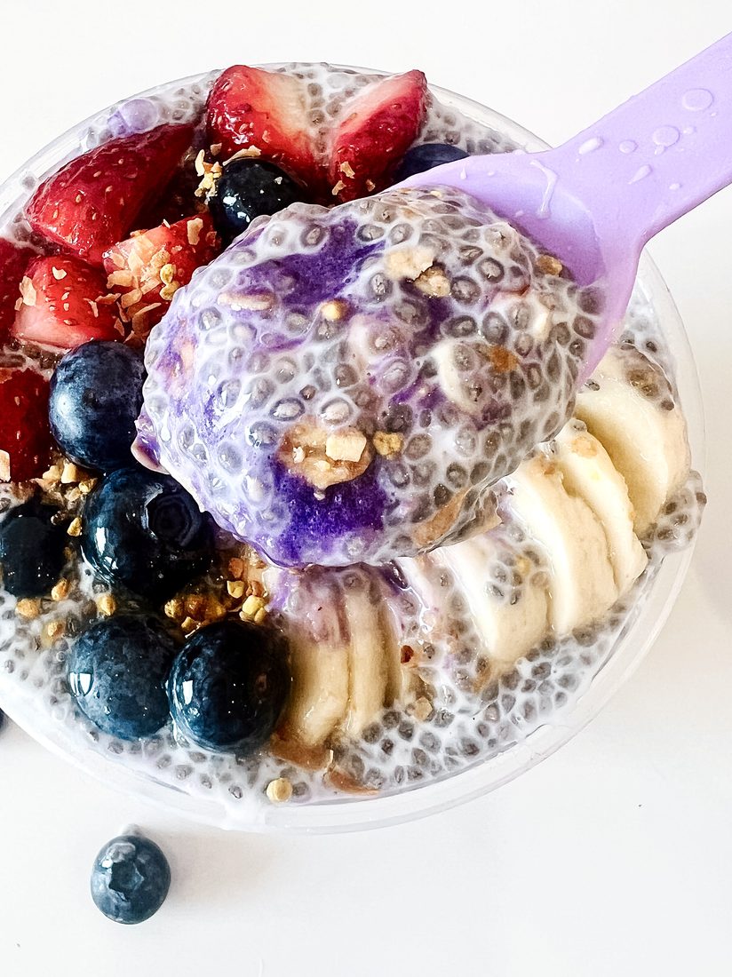 A spoonful of ube chia pudding over a fruit-topped bowl