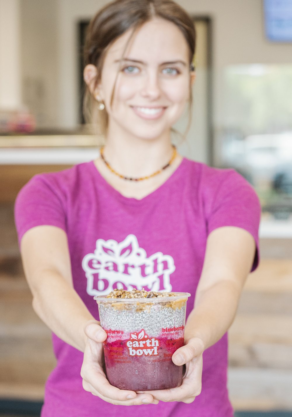 An Earth Bowl team member in a pink shirt holding out a layered bowl